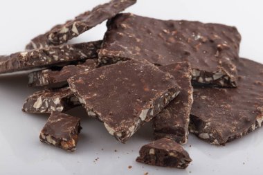 Kırık çikolata parçacıkları beyaz arka planda izole edilmiş.