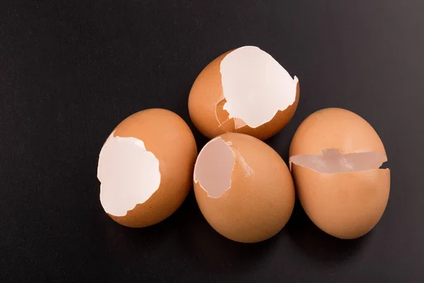 Broken egg in eggshell half isolated on black background