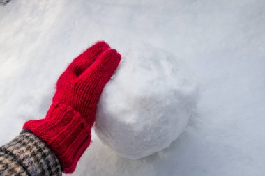 Kırmızı eldivenlerin elinde beyaz yuvarlak bir kartopu var.