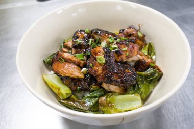 Izgara tavuk butları ve tabakta bir kase pirinç.