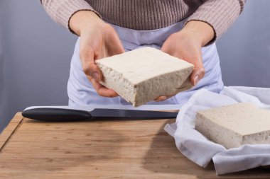Tofu on hand, white tofu on wooden cutting board