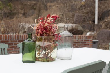 Dışarıdaki masada duran cam kavanozlardaki çiçekler.