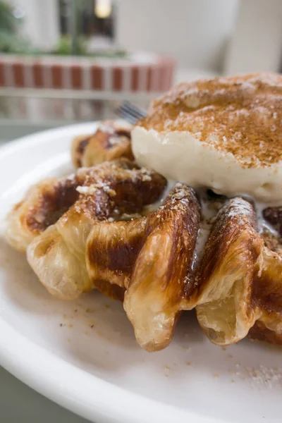 Bir top vanilyalı dondurmayla waffle ızgarasında pişmiş kruvasan hamuru.