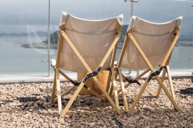 Kumsalda iki tane boş kamp sandalyesi.