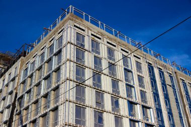 Mavi gökyüzü arka planında inşaat halindeki çok katlı beton apartman