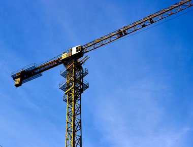 İnşaat kulesi vinci mavi gökyüzüne karşı inşaat alanında.