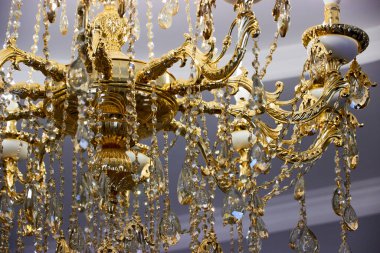 Altın kaplamalı, kristal kolyeli ve LED lambalı şık bir avize.