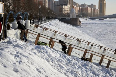 Nur-Sultan, Kazakistan: 3 Ocak 2021 - bir grup insan kışın nehir kıyısında kayarak ilerliyorlar