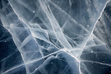 Donmuş bir gölün berrak buzundaki çatlakların dokusu