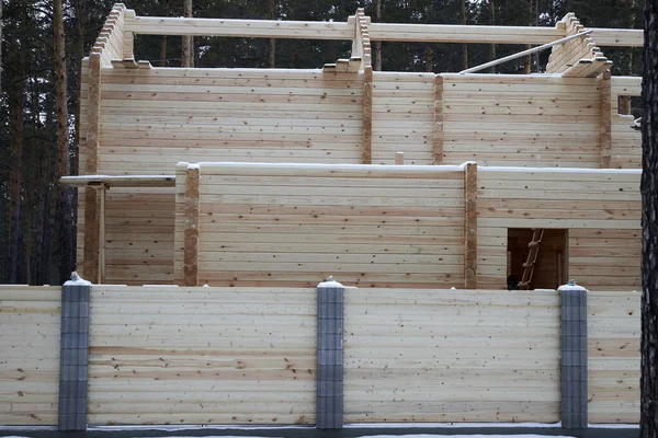 Casa en construcción hecha de vigas de madera en el bosque cercado con una valla de madera —  Fotos de Stock