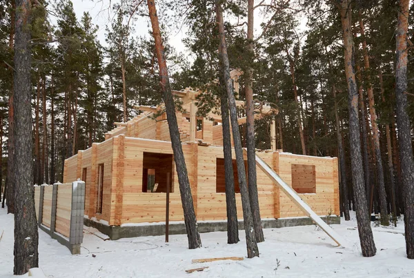 Строящийся дом из деревянных балок в лесу, огороженный деревянным забором — стоковое фото