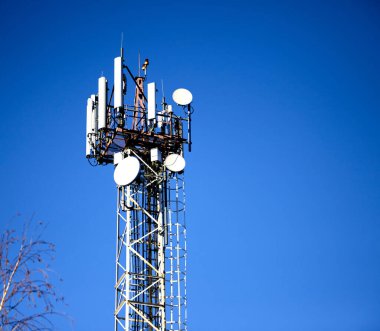 Mavi gökyüzü arka planında mobil iletişim antenleri olan metal kule