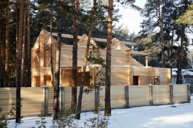 Kışın ormandaki ahşap kirişlerden yapılmış ahşap çitli bir ev yapım aşamasında.