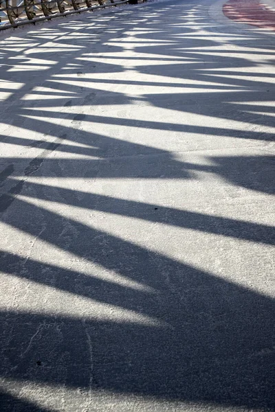 Yaya köprüsünün buzlu yolundaki metal bir çerçevenin geometrik gölgelerinin dikey görüntüsü — Stok fotoğraf