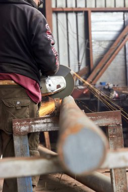 Açı öğütücüyle metal külçeleri kesen işçiler