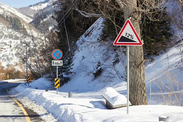 road signs steep descent and no stopping on a snowy mountain road