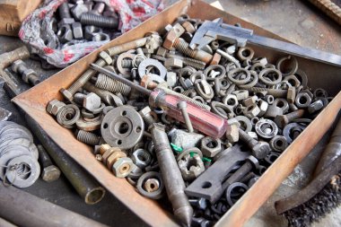 cıvatalar, fındıklar, boşluklar, kalibre, tornavida ve diğer aletler atölyedeki tezgahta