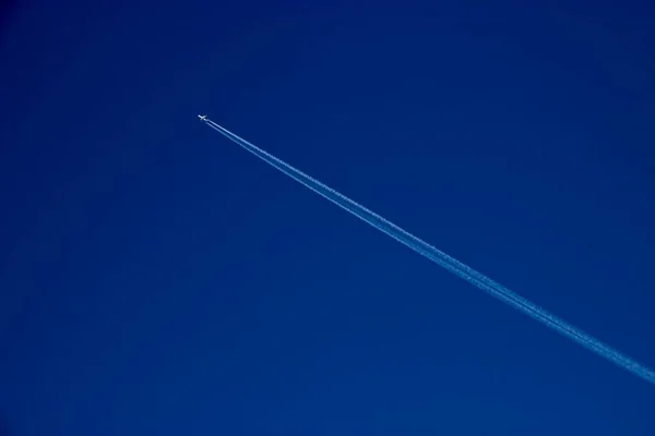 Flying plane with an inversion track on a blue sky background — Stock Photo, Image
