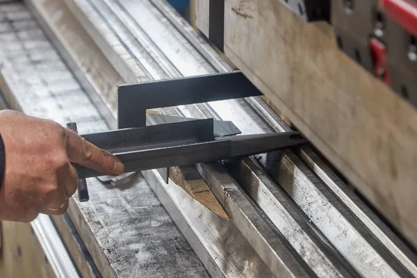 Werknemer met een metalen onderdeel op plaatbuigmachine — Stockfoto