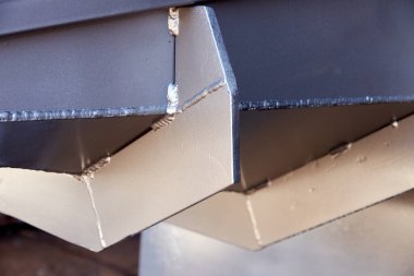 Gümüş rengine boyanmış metal bir yapı parçası. Yükleme kapağının dibindeki kabartmalar