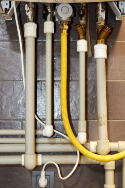 Gaz kazanına bağlı plastik sıcak ve soğuk su boruları ve gaz boruları.