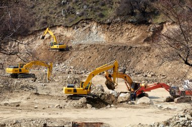 Kazıcılar bir dağ nehrinin kayalık kıyısını kazıyorlar.