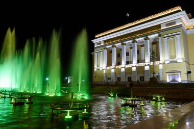Almaty, Kazakistan - 22 Mayıs 2021: Opera ve bale tiyatrosu ve çeşme gece aydınlanması ışığı altında. Gece şehir manzarası