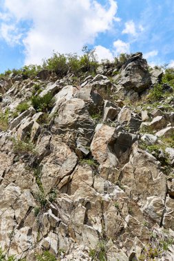 Dik kayalık ve bulutlu mavi gökyüzü
