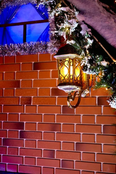 decorative lamp on the brick wall. Christmas tinsel decoration of house exterior