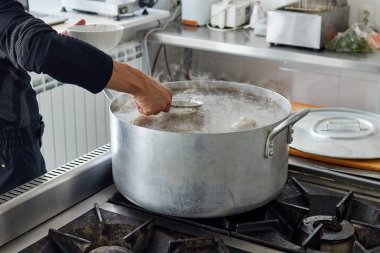 Aşçı et suyunun yüzeyinden köpük kaynatıyor. 