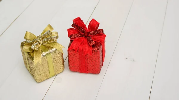 白色木制桌子上的红色和金色礼品盒 — 图库照片