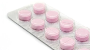 Beyaz arka planda pembe hap, seçici odak.