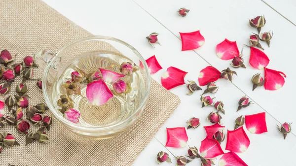 Beyaz ahşap bir masada pembe bir fincan çay..