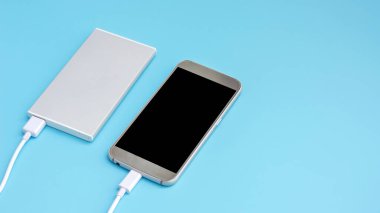 akıllı telefon ve güç bankası mavi arkaplan üzerindeki mobil aygıtları şarj etmek için.