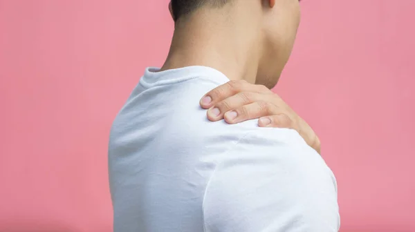 男はピンクの背景に彼の肩の痛みを感じる — ストック写真