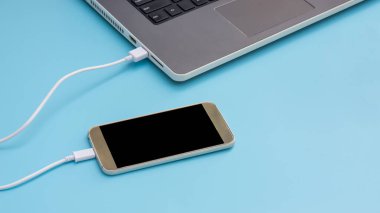 Mavi arka planda dizüstü bilgisayara bağlanan akıllı telefon.