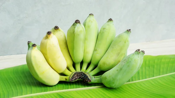 Muz yapraklı ve ahşap masadaki Pisang Awak muzu..