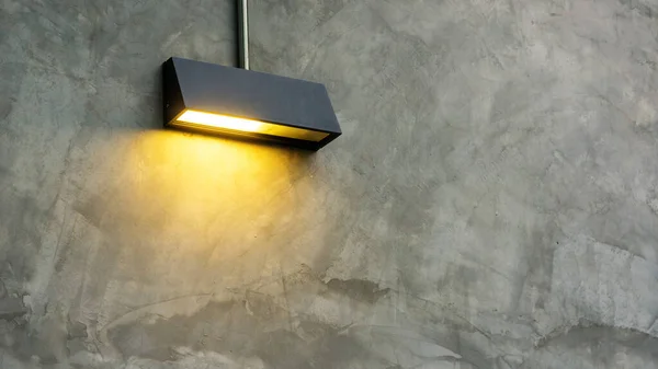 Gri duvarda siyah lamba parlıyor.