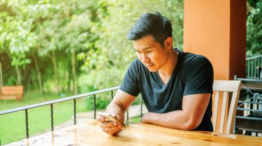 Asyalı gençler terasta akıllı telefon kullanıyor..