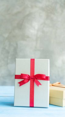 Mavi ahşap bir masada gümüş ve altın bir hediye kutusu..