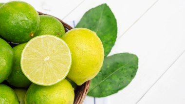 Beyaz ahşap bir masada sepetteki yeşil kireç.