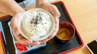 Ahşap masa arkasında Japon pirinci taşıyan bir adam..