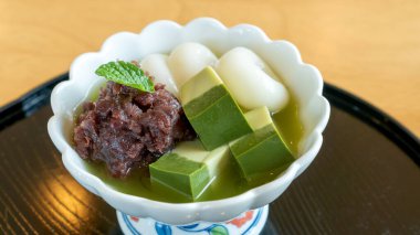 Japon tatlısı (Matcha, dango, tofu ve kırmızı fasulye) ahşap bir masada bir kasede..
