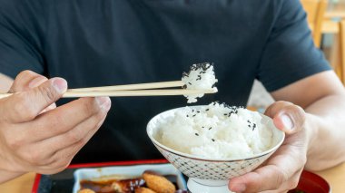 Japon yemek arka planında yemek çubukları ve bir kase Japon pirinci tutan adam..