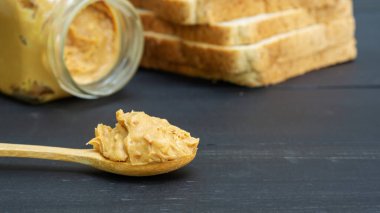 Fıstık ezmesi ve siyah ahşap bir masada tam buğday ekmeği.