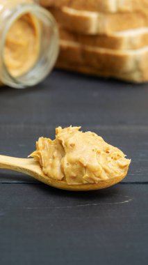 Fıstık ezmesi ve siyah ahşap bir masada tam buğday ekmeği.