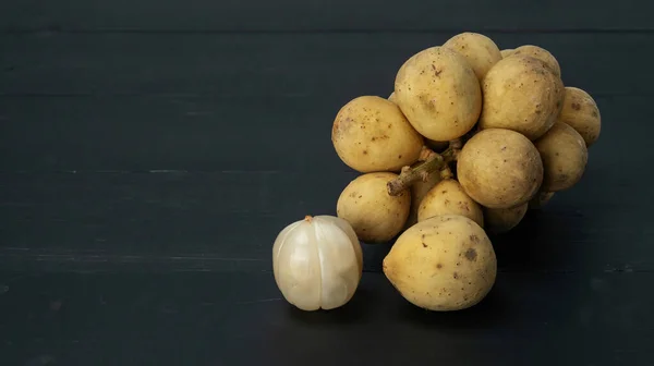 Siyah ahşap bir masada Lansium parazit meyvesi..