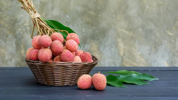 Siyah ahşap bir masada kırmızı liçi..