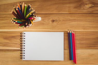 Ahşap masada renkli kalem ve çizim defteri