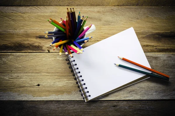 Lápis de cor e caderno de esboços em fundo de madeira — Fotografia de Stock